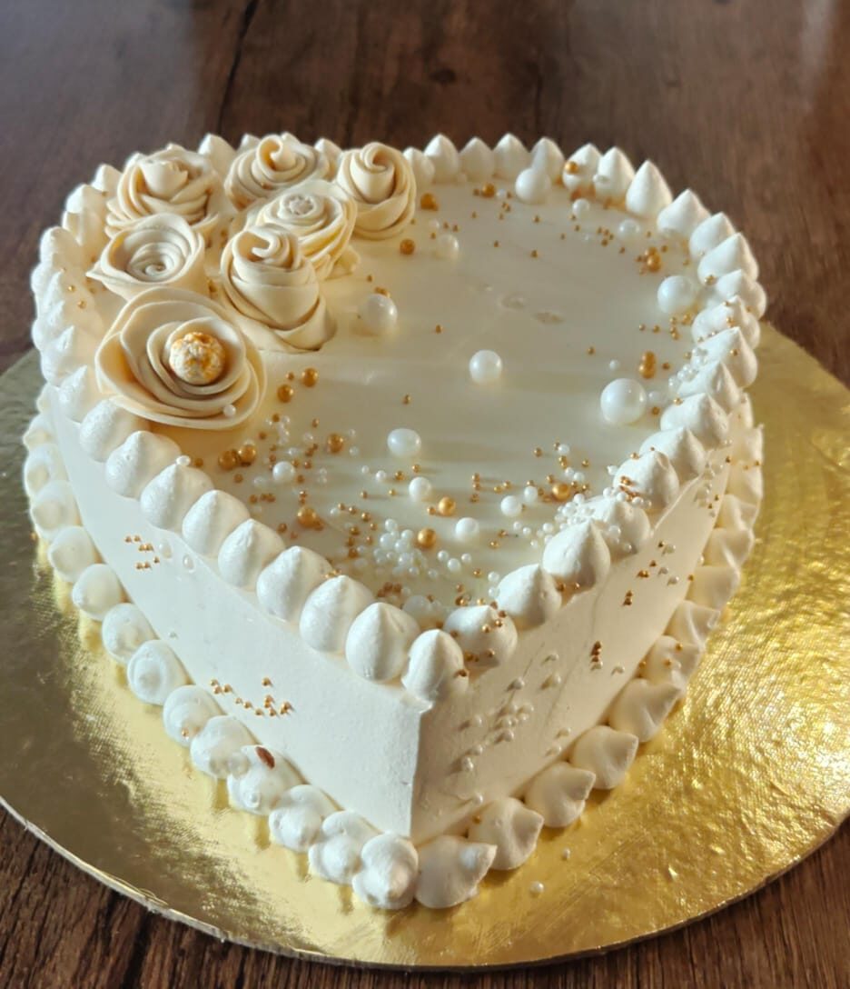 Elegant white heart-shaped cake with piped rosettes and gold pearls