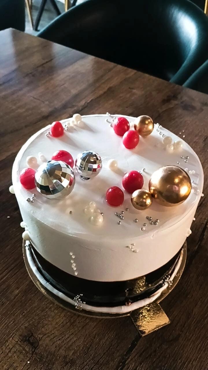 Cake decorated with metallic disco-ball spheres and red cherries