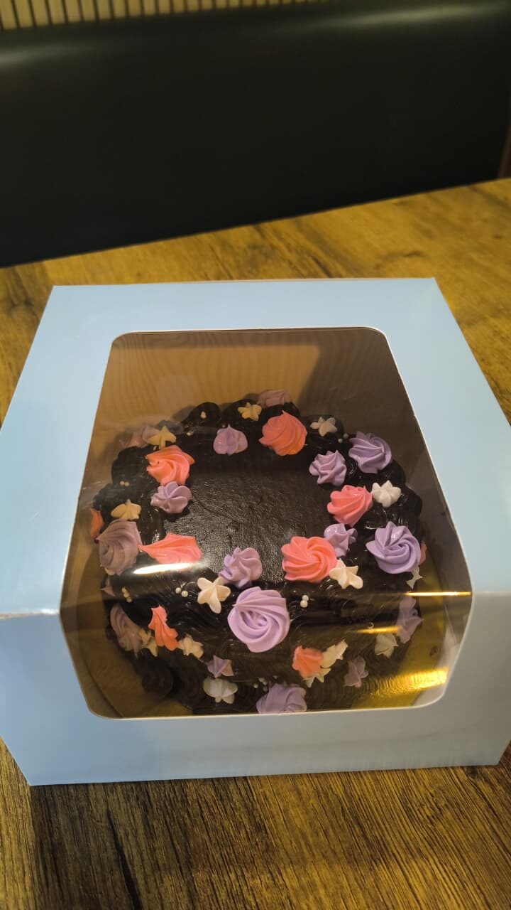 Chocolate cake with pastel piped flowers in a gift box