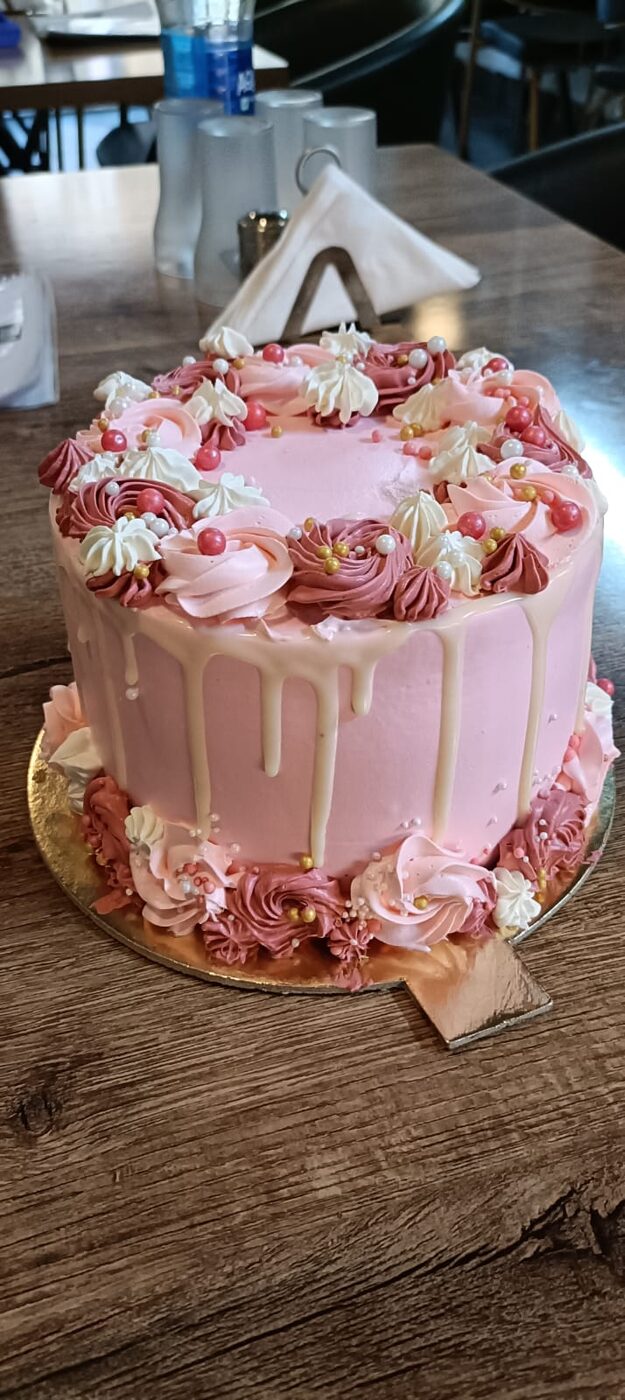 Pink drip cake with rosette piping and gold accents